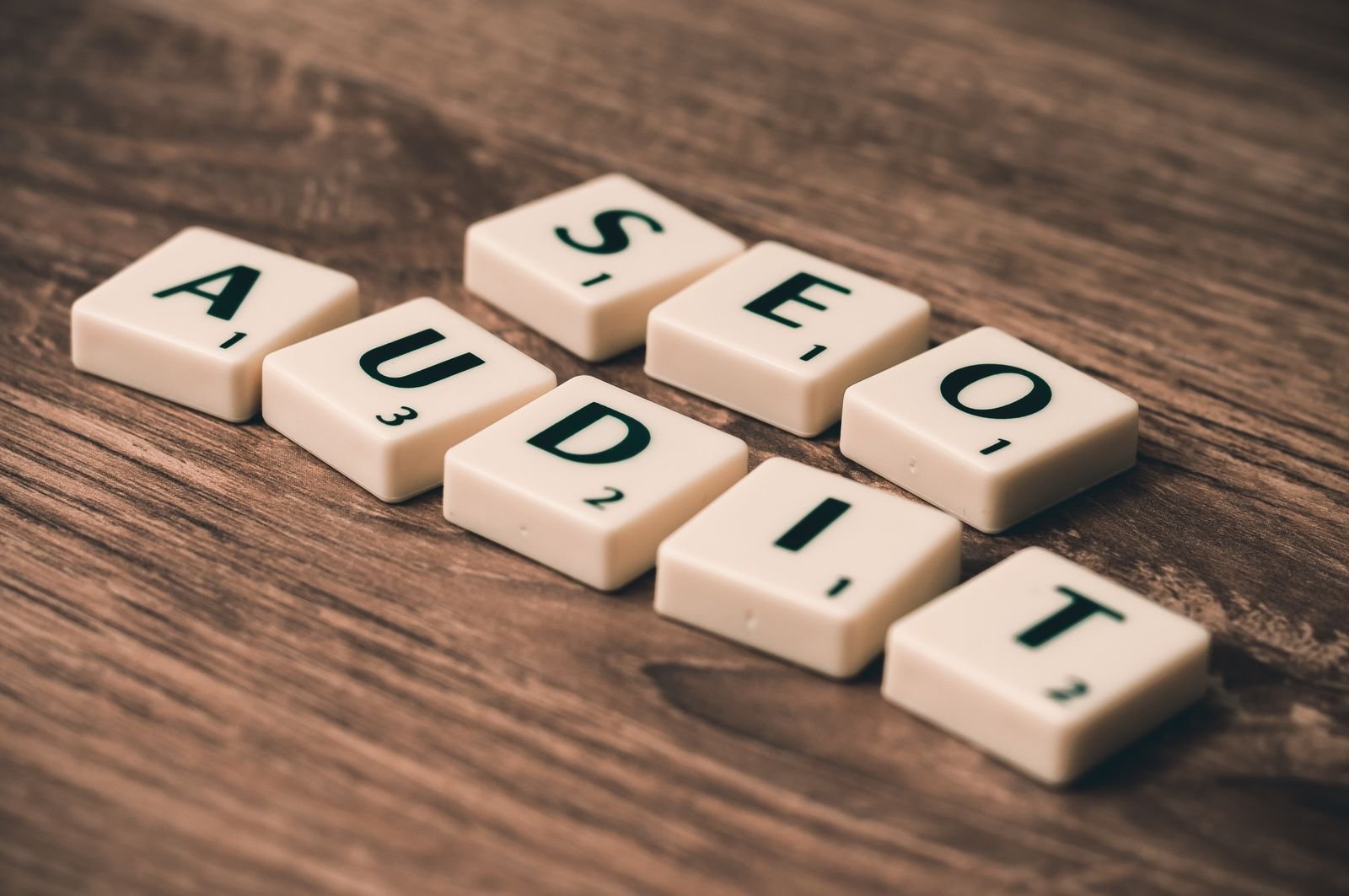 White letter blocks spelling SEO AUDIT on a wooden surface, representing a website AI visibility audit