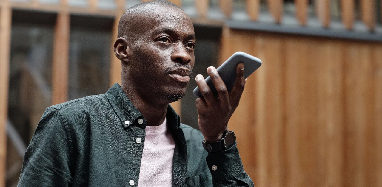 Man checking his phone outdoors, representing someone asking an AI assistant a best-service-near-me question
