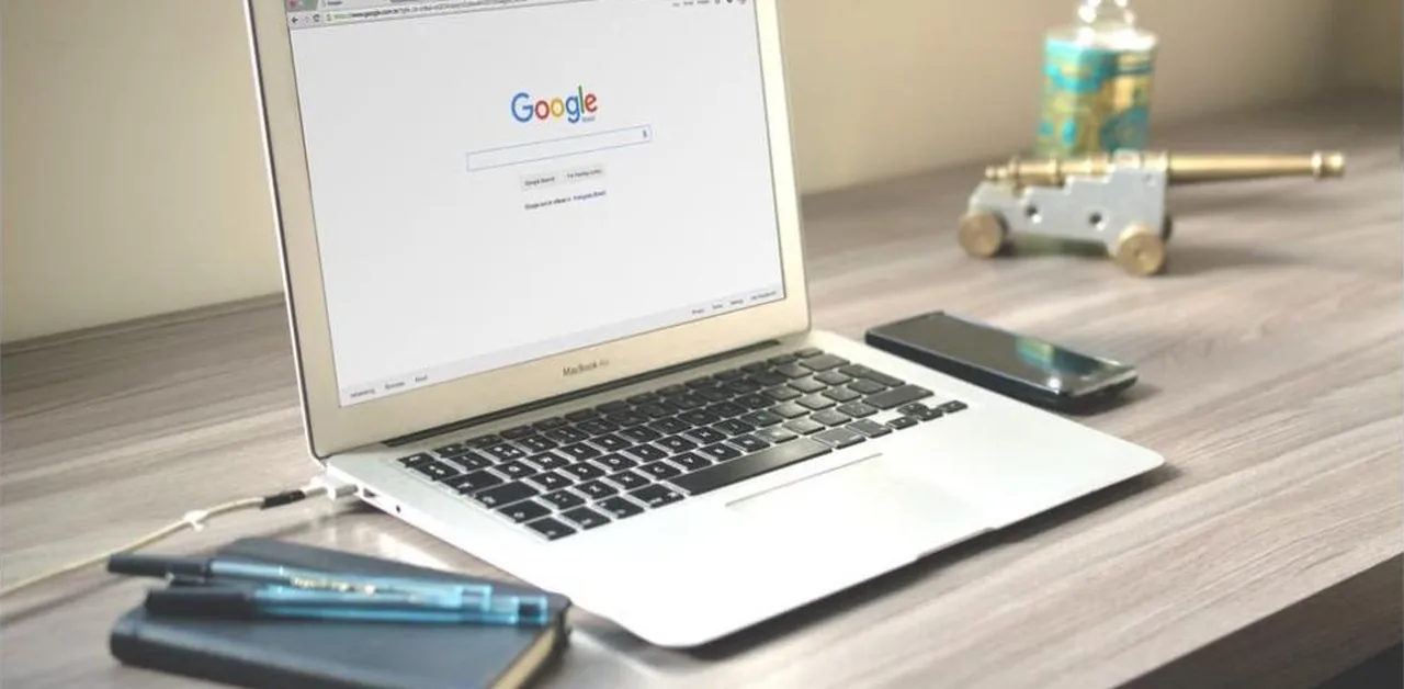 Laptop displaying a Google search homepage on a wooden desk, illustrating how AEO helps content get cited in AI-powered search results