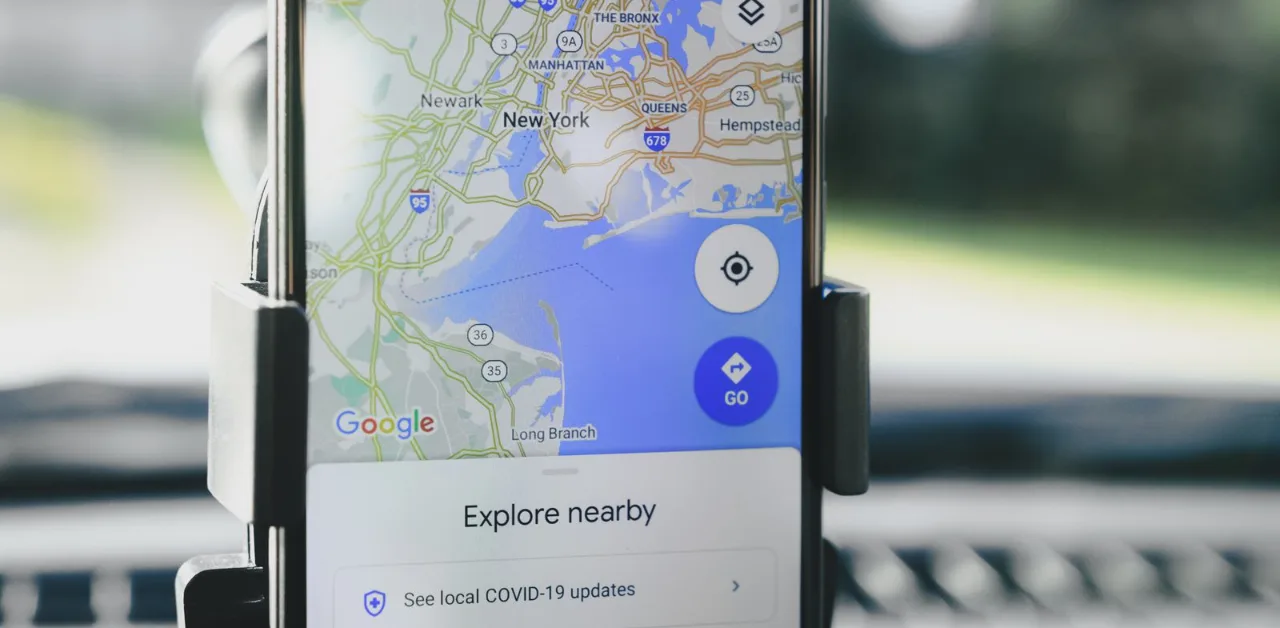 Smartphone mounted in a car showing Google Maps navigation for a local business search