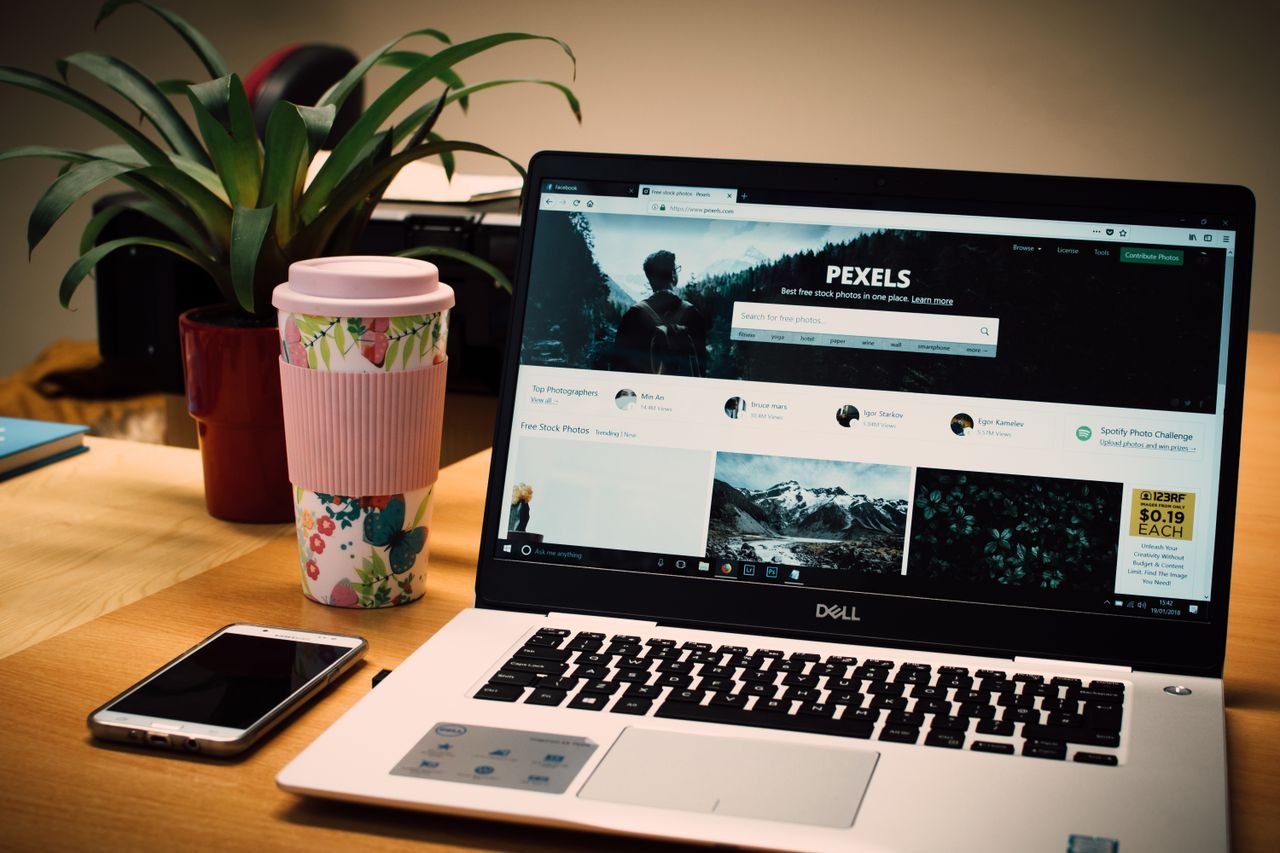 Home A tidy desk setting with a laptop showing a stock photo website and a smartphone.