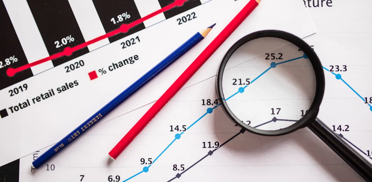 Growth chart and sales percentage graphs being analyzed with a magnifying glass, representing SEO ROI calculation