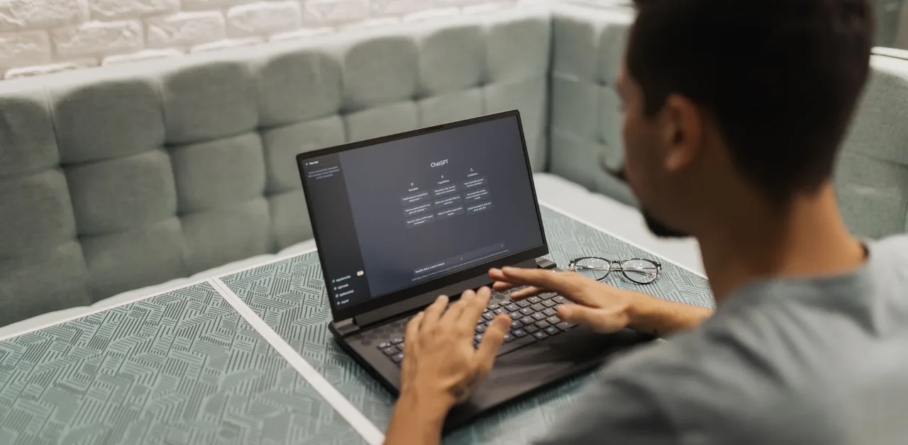 Man typing a question into an AI chat assistant on a laptop