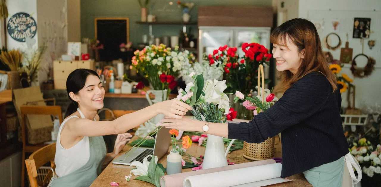 Two small business owners working at a local flower shop counter with a laptop